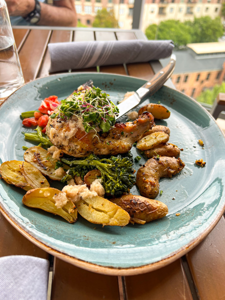 Roasted chicken with potatoes on blue plate at Up on the Roof in Greenville, SC