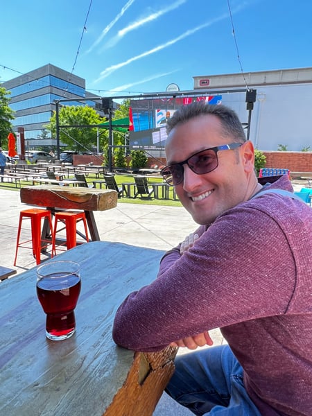Tom, a white brunette male in red sweater and sunglasses, drinking outside at Yee-Haw Brewing Company in Downtown Greenville, SC